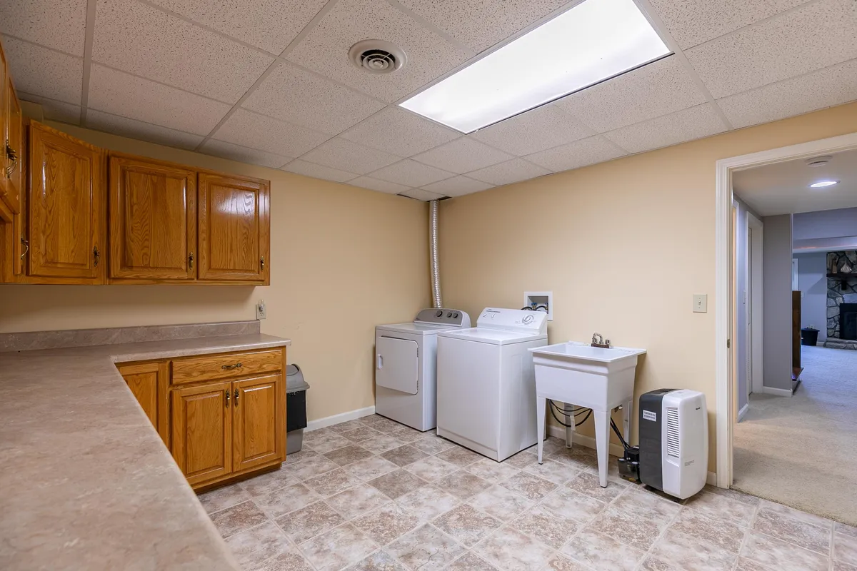 A practical laundry area equipped with a washer, dryer, sink, and storage cabinets, providing a convenient solution for extended stays.