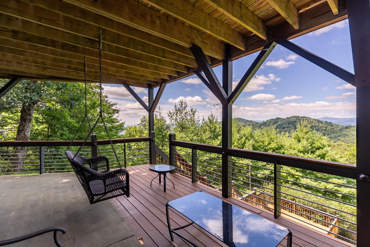 A peaceful outdoor seating area featuring a hanging chair and glass table, all set against a stunning mountain backdrop. The scene is serene, inviting guests to unwind, read, or simply take in the views after a day of adventure.