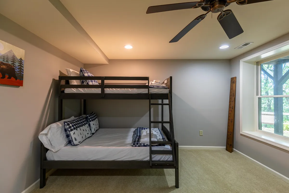 A fun and inviting bunk room with a sturdy bunk bed, playful bear artwork, and a sunlit window. The room is perfectly suited for groups or families, offering a cheerful sleeping space.