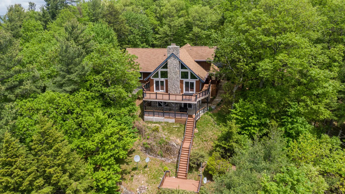 This image shows the exterior of the house nestled among tall trees, with a staircase leading up to a welcoming porch. The natural surroundings and inviting architecture highlight the cabin’s connection to outdoor adventure and relaxation.